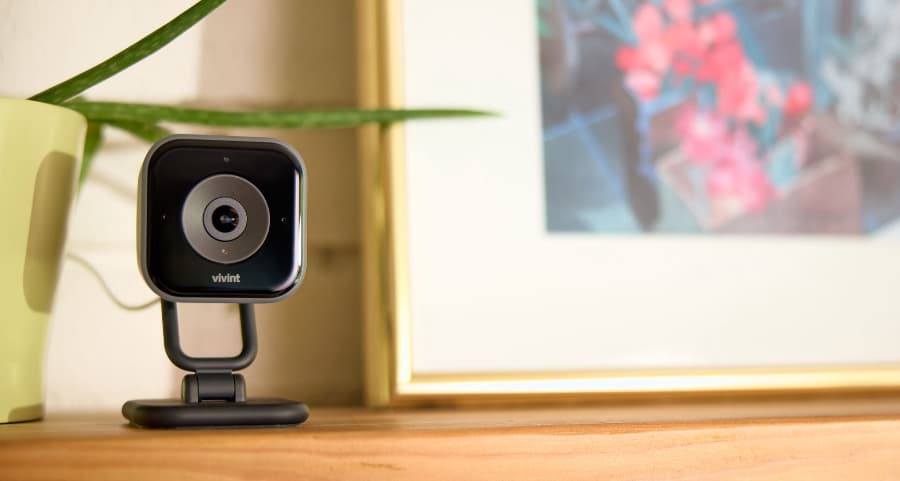 Vivint indoor camera sitting on a mantel next to a framed picture